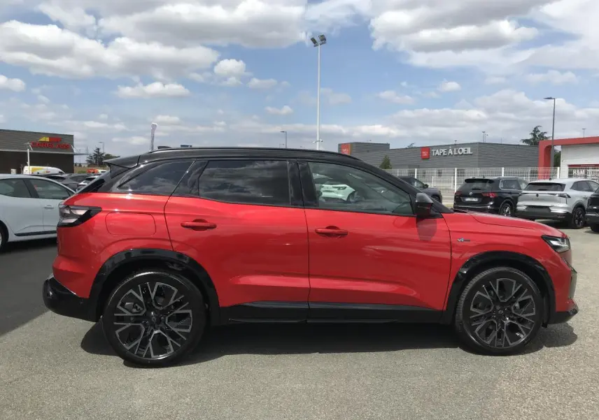 Profil droit du Renault Austral 2025 bi-ton rouge et noir avec jantes alliage noires et toit noir brillant.