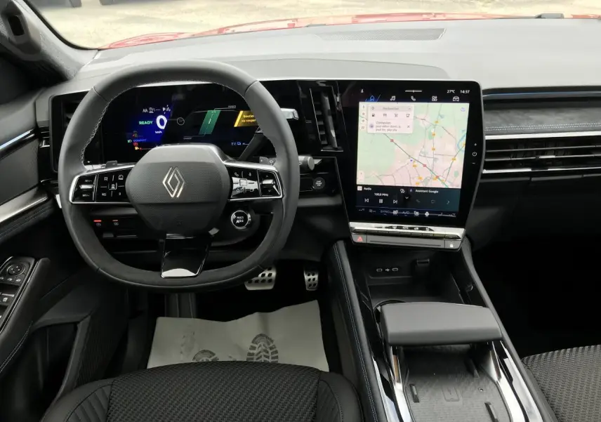 Vue intérieure avant du tableau de bord du Renault Austral rouge noir, avec écran tactile vertical et volant multifonction.