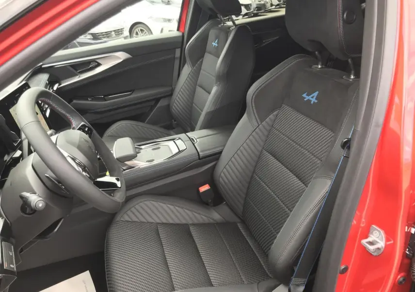 Vue intérieure côté conducteur du Renault Austral 2025 rouge noir, sièges sport Esprit Alpine avec surpiqûres bleues et logo brodé.