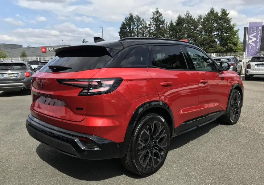 Vue 3/4 arrière droite du Renault Austral rouge et noir avec jantes alliage noires et toit noir métallisé.