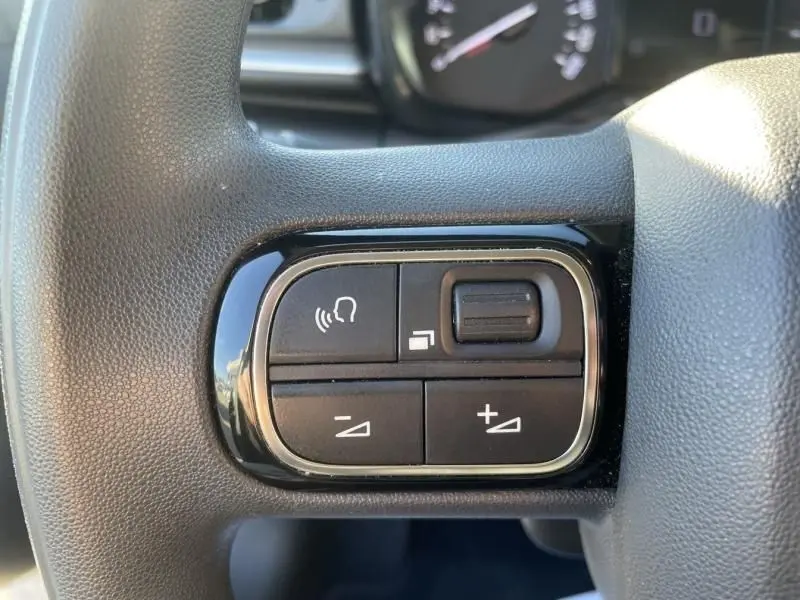 Gros plan sur les commandes multifonctions à gauche du volant gris foncé de la Citroën C3 1.2 PureTech 2021.
