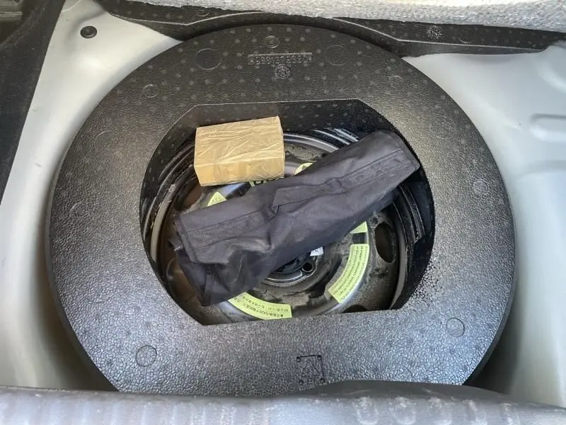 Vue plongeante sur la roue de secours et le rangement sous le coffre d'une Citroën C3 gris foncé 2021.