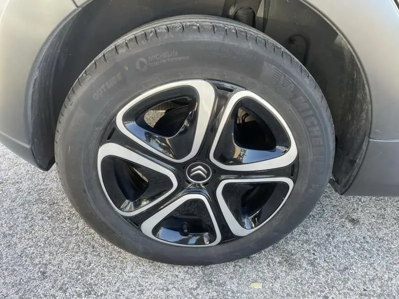 Gros plan sur la roue avant droite d'une Citroën C3 gris foncé, jante noire et argent avec logo Citroën central.