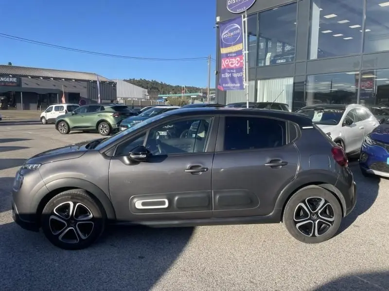 Vue de profil côté gauche d'une Citroën C3 gris foncé 2021 avec protections latérales caractéristiques et jantes noires.