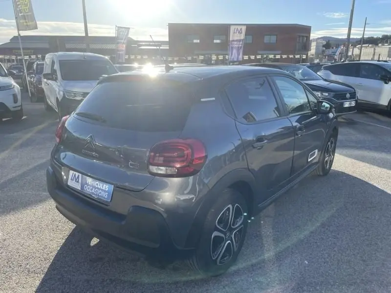 Vue 3/4 arrière droite d'une Citroën C3 gris foncé 2021 avec jantes distinctives et vitres teintées.