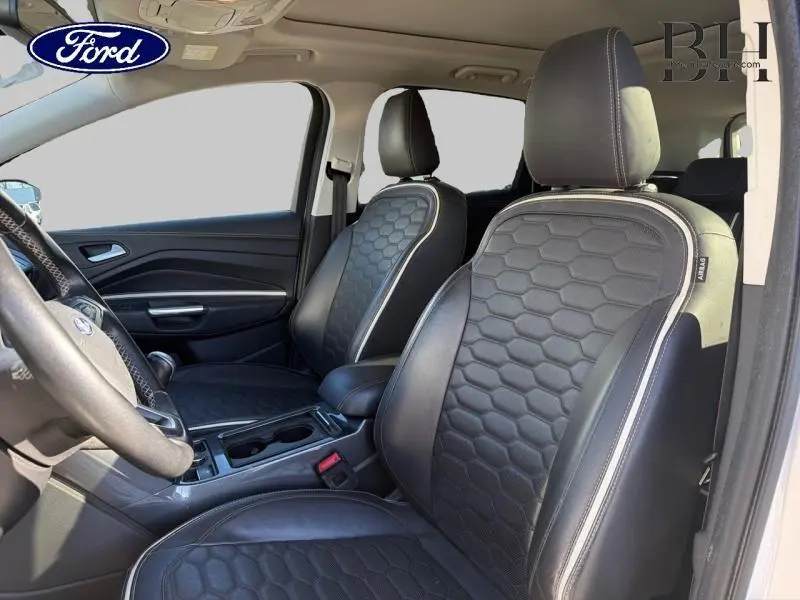 Vue intérieure côté conducteur du Ford Kuga 2017 avec sièges sport en cuir noir à motifs hexagonaux et surpiqûres claires.