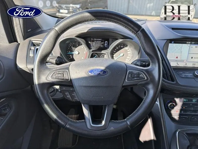 Vue intérieure centrée sur le volant cuir multifonction du Ford Kuga 2017 avec tableau de bord et écran GPS visible.