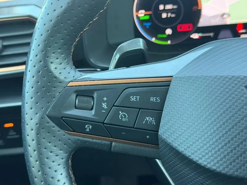 Gros plan sur le côté gauche du volant perforé noir avec commandes de régulateur et bande décorative cuivre du CUPRA Formentor.