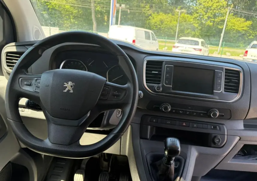 Vue intérieure du tableau de bord du Peugeot Expert Fourgon blanc, volant cuir multifonctions et levier de vitesse manuel visibles.