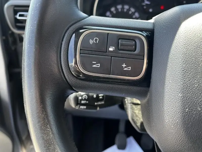 Gros plan sur les commandes au volant du Citroën Berlingo XL gris métal 2021, avec boutons de réglage et commande vocale.