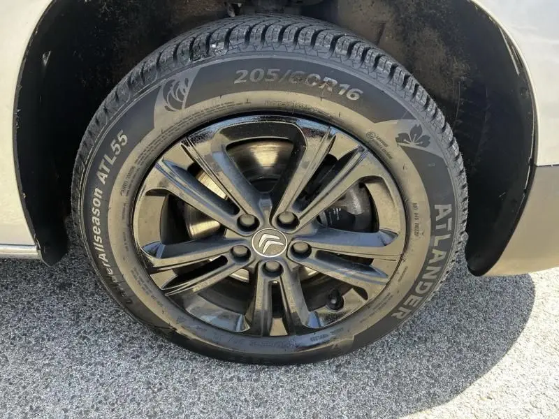 Gros plan sur la roue avant droite du Citroën Berlingo gris métal, mettant en valeur la jante noire et le pneu Allseason.