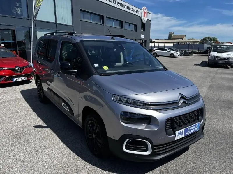 Vue 3/4 avant droit du Citroën Berlingo XL gris métal 2021 avec signature lumineuse distinctive et jantes noires.