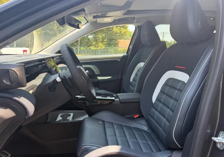 Vue intérieure côté conducteur du Citroën C5 Aircross gris 2026, sièges cuir noir avec surpiqûres blanches et volant multifonctions.