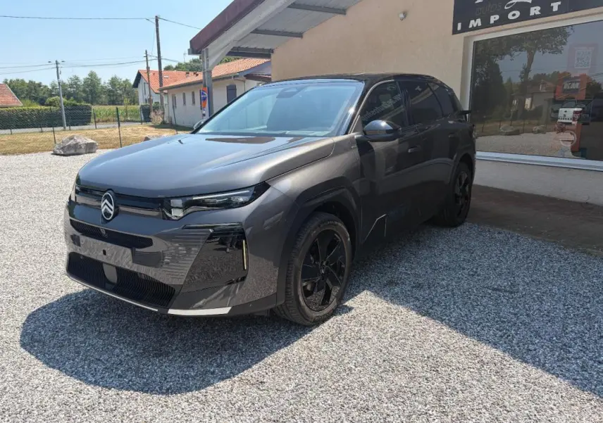 Vue 3/4 avant d’un Citroën C5 Aircross gris 2026 avec jantes noires et toit ouvrant panoramique visible.