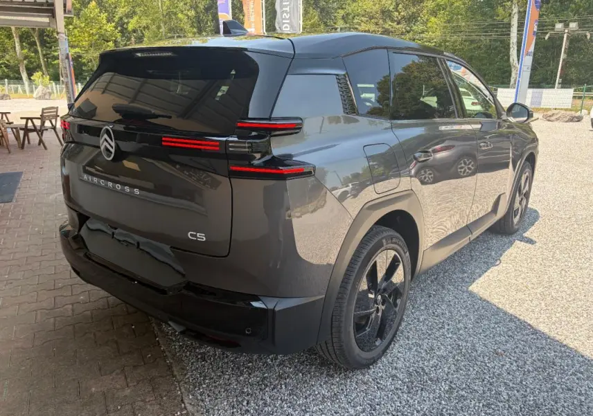 Vue 3/4 arrière droite d'un Citroën C5 Aircross gris 2026 avec feux arrière LED et jantes noires 19 pouces.