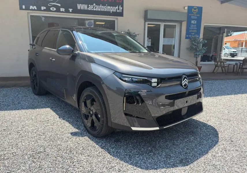 Citroën C5 Aircross gris en 3/4 avant droit, avec jantes noires et calandre moderne, stationné devant un bâtiment.