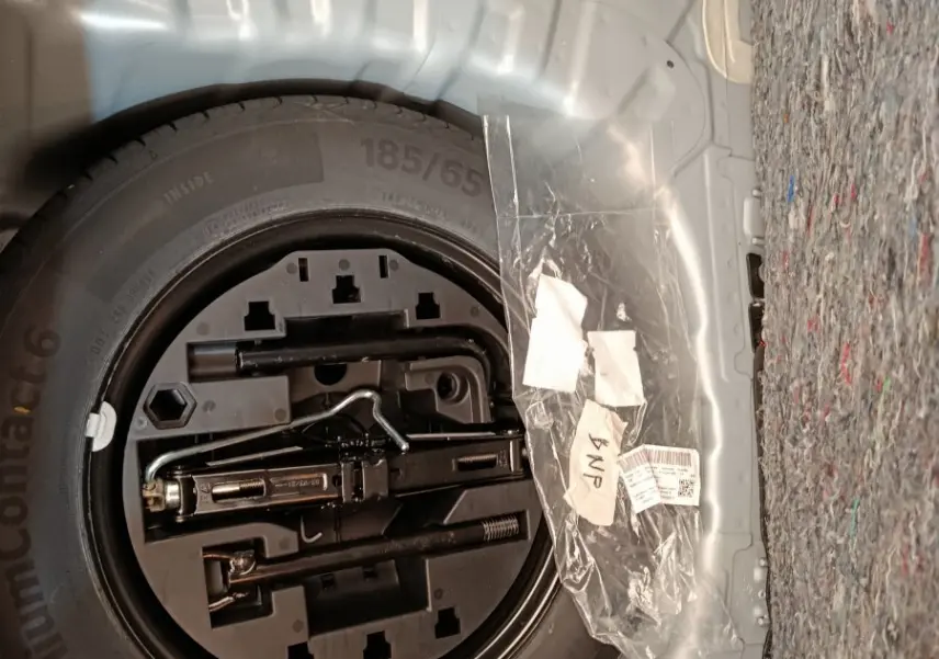Vue rapprochée de la roue de secours et des outils dans le coffre gris clair d’une Renault Clio Business TCe 100 2021.