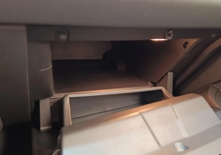 Gros plan sur la boîte à gants ouverte de la Renault Clio Business TCe 100 2021, intérieur gris sombre.