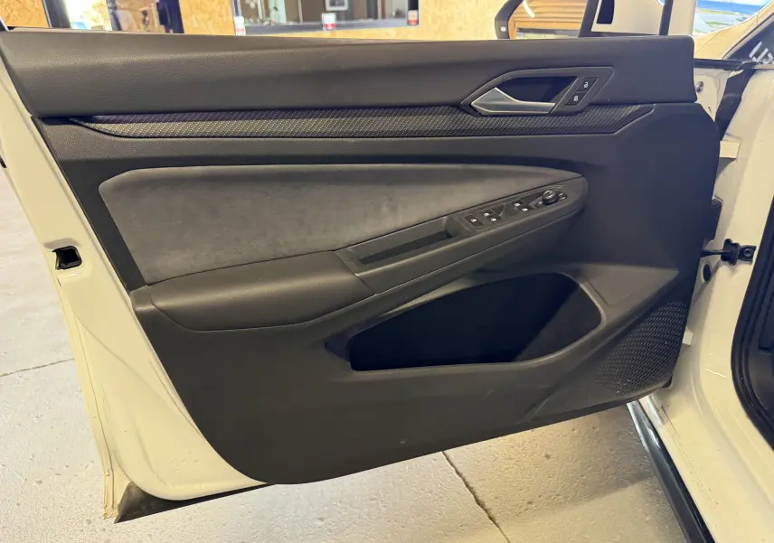 Vue intérieure de la porte avant gauche blanche d'une Volkswagen Golf 2.0 TDI 150 DSG7 R-Line avec commandes électriques.