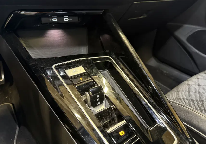 Vue rapprochée de la console centrale noire brillante avec levier de vitesses DSG et bouton start/stop dans une Volkswagen Golf blanche.