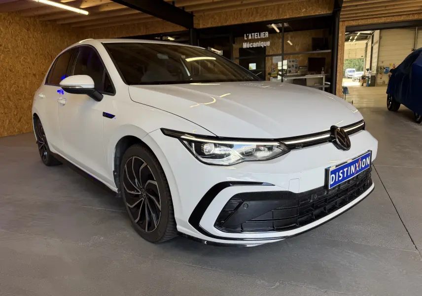 Volkswagen Golf 2.0 TDI R-Line blanche vue 3/4 avant droit, avec jantes noires et calandre distinctive R-Line.