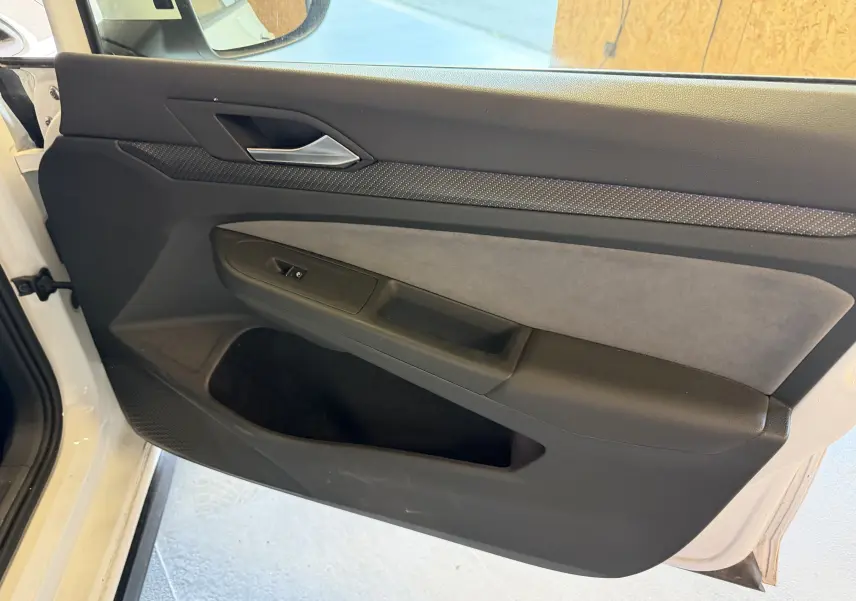 Vue intérieure côté gauche de la porte avant blanche de la Volkswagen Golf 2.0 TDI R-Line avec garniture noire et grise.