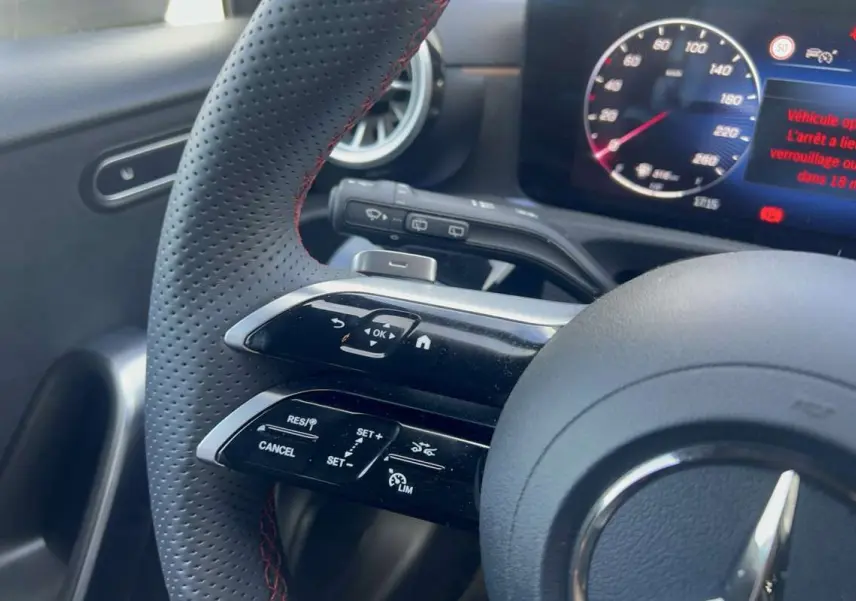 Gros plan sur le volant cuir perforé avec commandes multifonctions et tableau de bord digital de la Mercedes Classe A AMG Line 2025.