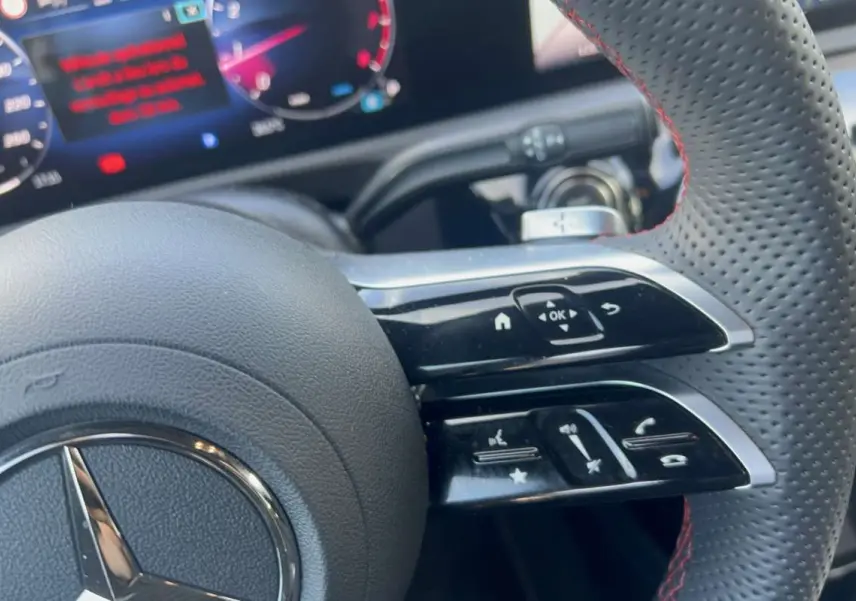 Gros plan sur le volant cuir perforé AMG Line de la Mercedes Classe A 200, avec commandes multifonctions et palettes au volant.