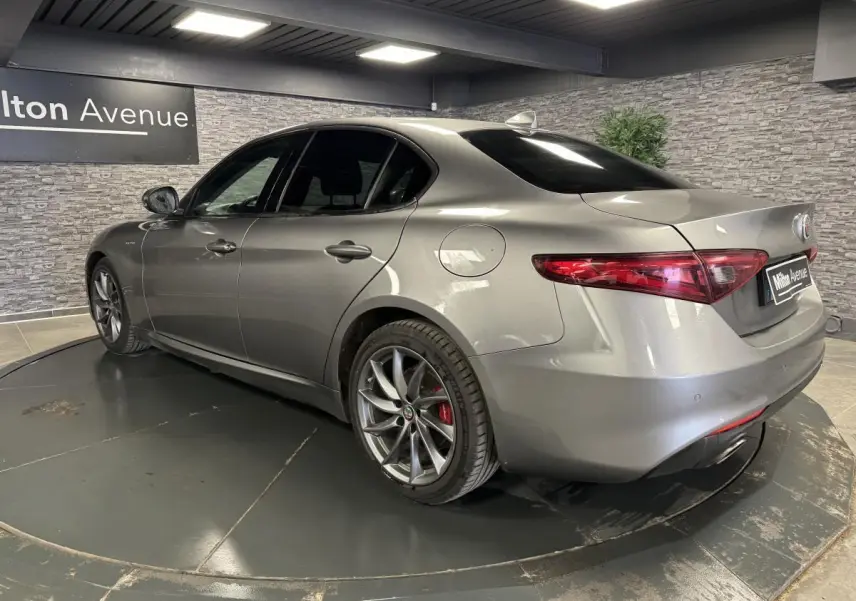 Vue 3/4 arrière droite de l'Alfa Romeo Giulia gris métallisé avec jantes alliage 18 pouces Aero Scuro et vitres surteintées.