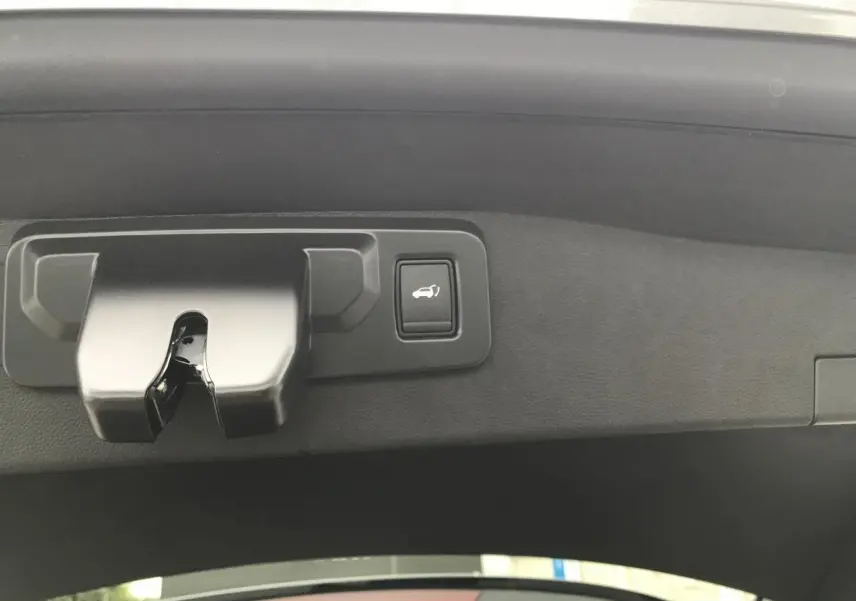 Gros plan sur la serrure et le bouton d'ouverture électrique du hayon du Renault Austral gris bi-ton.