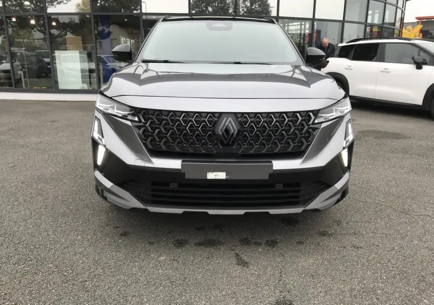 Vue frontale du Renault Austral gris métallisé avec calandre noire à motif hexagonal et feux LED allumés.