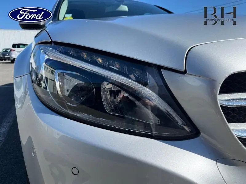Gros plan sur le phare avant droit argent iridium d'une Mercedes Classe C 200 d Business de 2016.