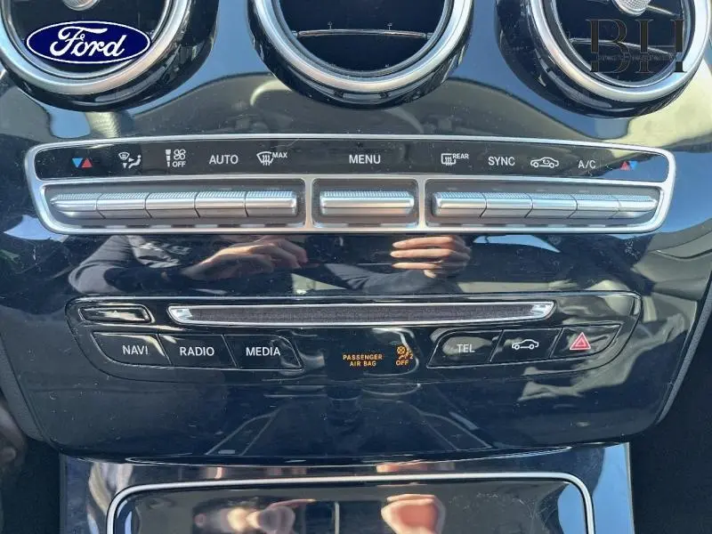 Vue rapprochée de la console centrale noire brillante d'une Mercedes Classe C 200 d Business avec commandes climatisation et multimédia.