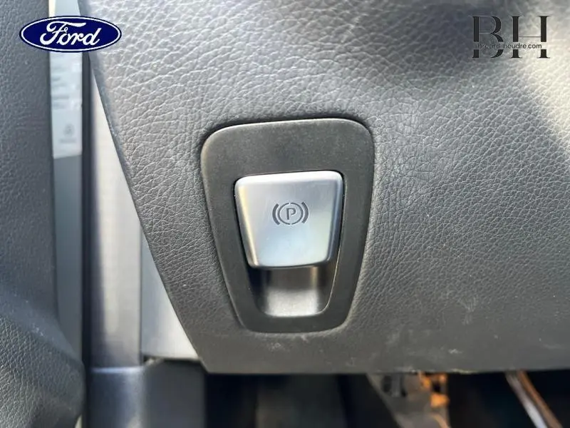 Gros plan sur le bouton de frein de stationnement électronique dans l'habitacle d'une Mercedes Classe C 200 d Business argent iridium.