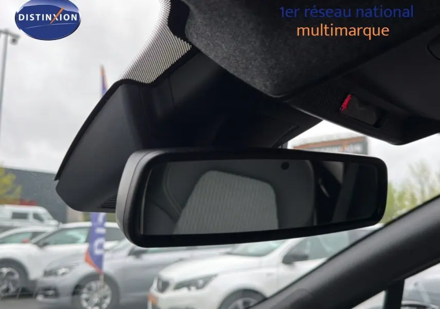 Vue intérieure centrée sur le rétroviseur intérieur d’une Renault Clio gris Rafale Metal, avec siège en tissu visible en reflet.