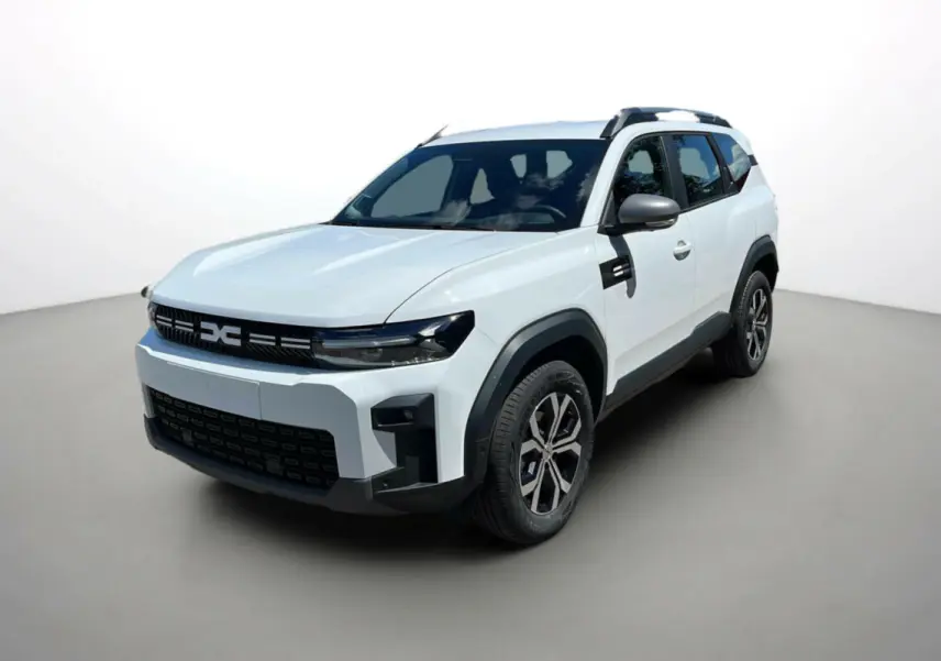 SUV Dacia Bigster blanc glacier en 3/4 avant droit, avec barres de toit et jantes alu 17 pouces visibles.