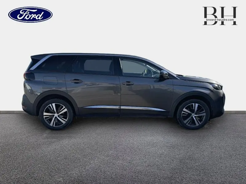 Profil droit du Peugeot 5008 gris Platinium 2022 avec jantes alliage et vitres arrière surteintées.