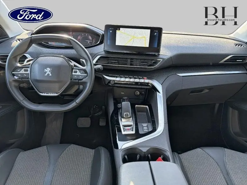 Vue intérieure frontale du poste de conduite du Peugeot 5008 gris Platinium avec volant compact et écran tactile GPS central.