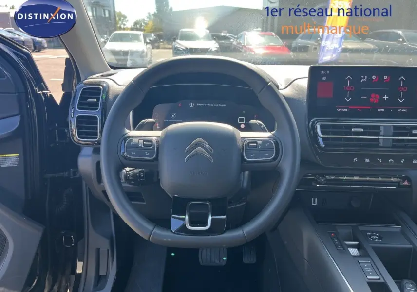 Vue intérieure centrée sur le volant noir du Citroën C5 Aircross 2025, avec tableau de bord digital et écran tactile.