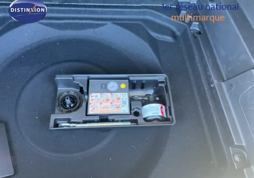Compartiment de coffre noir avec kit de réparation pneus intégré dans un Citroën C5 Aircross 2025 hybride.