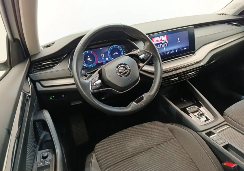Vue intérieure côté conducteur de la Skoda Octavia 2023, volant cuir multifonctions et écran tactile central lumineux.
