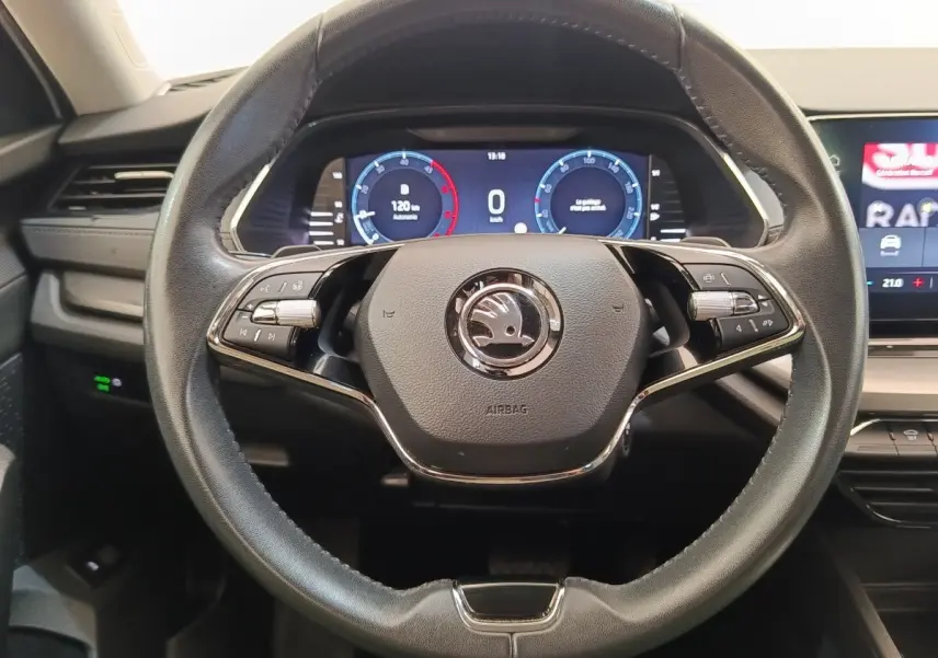Vue rapprochée du volant cuir et alu multifonctions de la Skoda Octavia 2023 avec tableau de bord numérique éclairé.