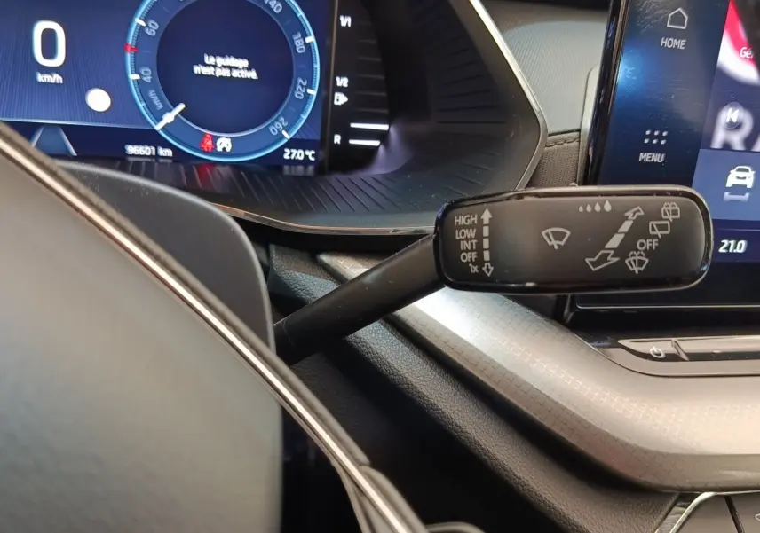 Gros plan sur le combiné d’instruments et la commande d’essuie-glace dans l’habitacle d’une Skoda Octavia blanche 2023.