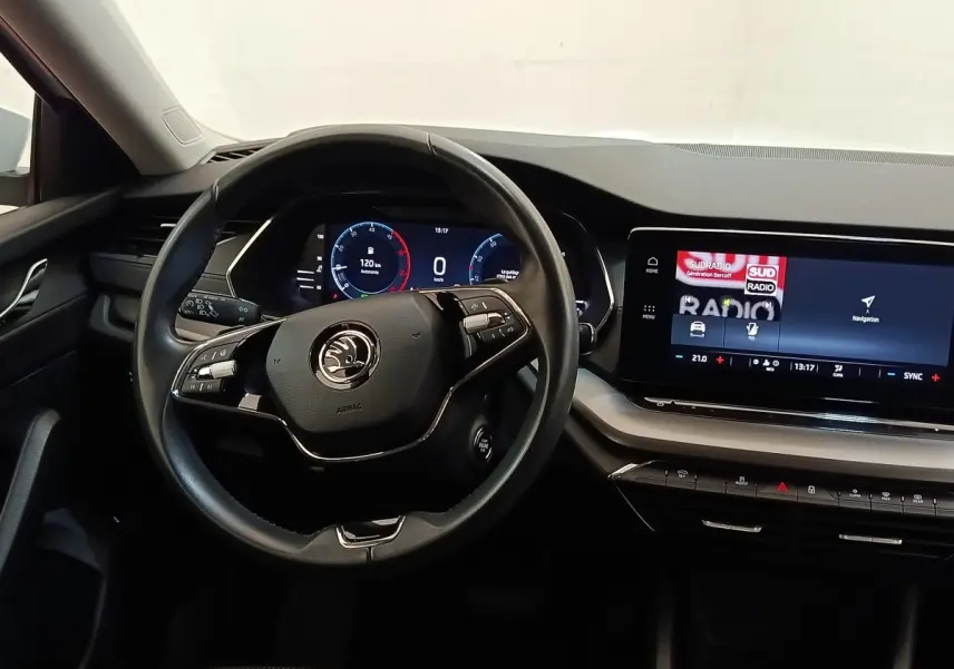Vue intérieure centrée sur le volant cuir et alu multifonctions de la Skoda Octavia 2023 avec tableau de bord numérique et écran tactile.