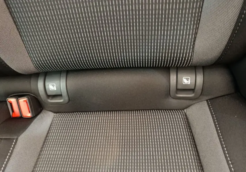 Gros plan sur la banquette arrière noire à motifs rayés avec attaches Isofix et boucles de ceinture rouges.