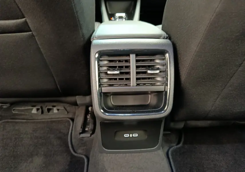 Vue rapprochée des aérateurs arrière et ports USB noirs sur la console centrale entre les sièges arrière d'une Skoda Octavia blanche.