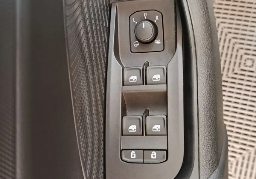Gros plan sur les commandes de réglage des rétroviseurs et vitres côté conducteur d'une Skoda Octavia blanche 2023.