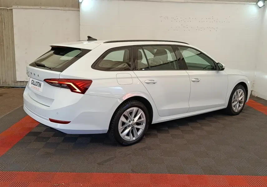 Vue 3/4 arrière droite d'une Skoda Octavia break blanche 2023 avec feux LED et jantes alliage.