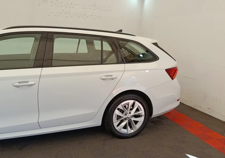 Vue latérale droite d'une Skoda Octavia break blanche 2023, mettant en valeur la roue arrière et les vitres teintées.