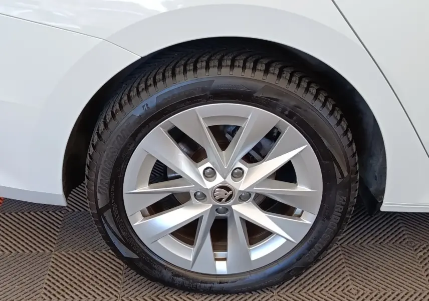 Gros plan sur la roue avant droite d'une Skoda Octavia blanche, avec jante alliage à dix branches.